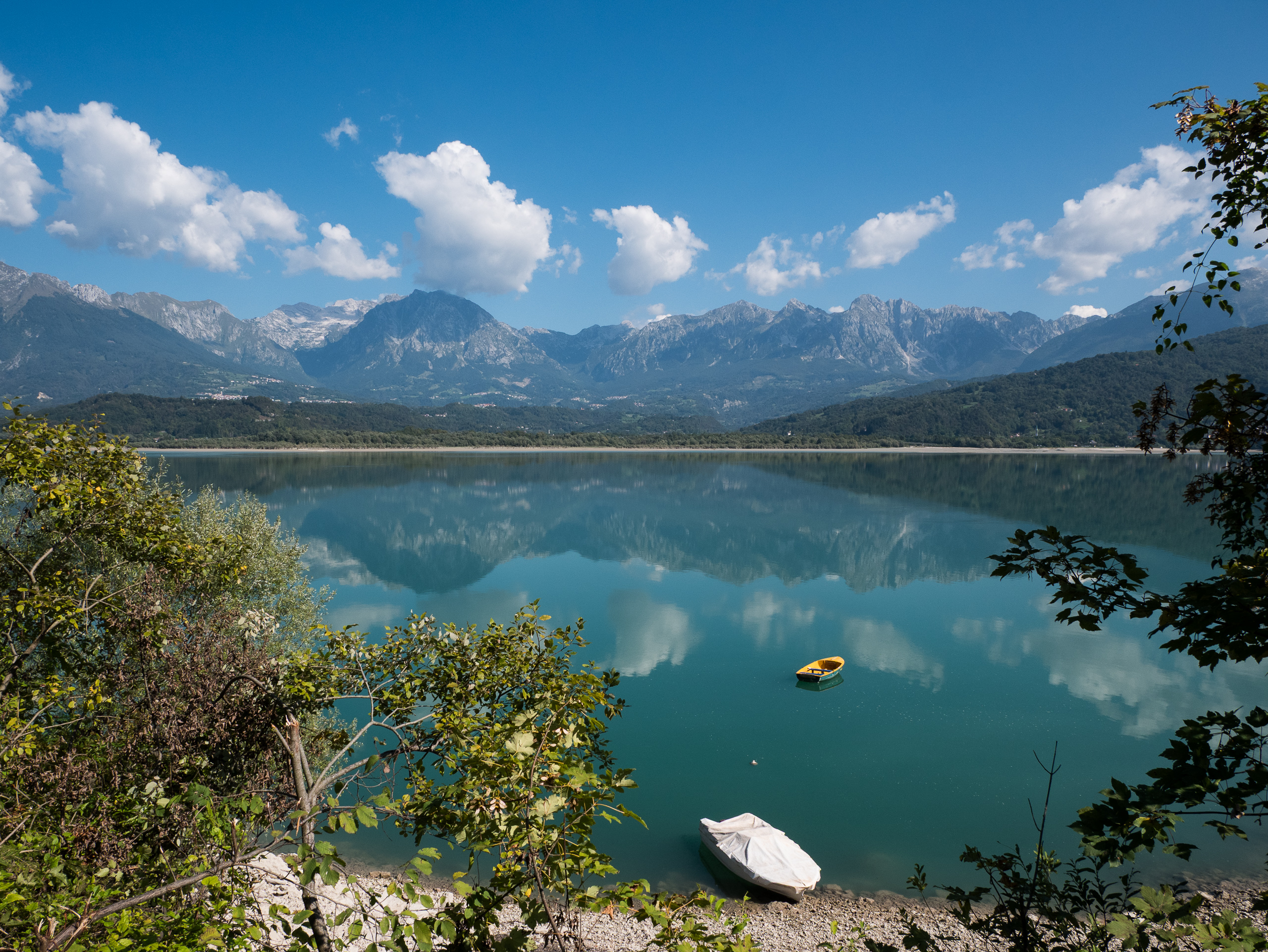 Der türkise Lago di Santa Croce mit einem gelben Boot